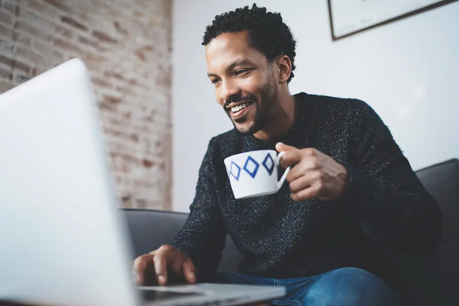 Man smiling while working on laptop during telehealth counseling session