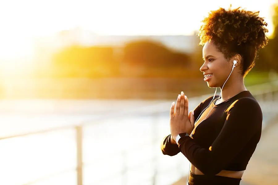 Woman meditating at sunrise near water for stress relief and mindfulness
