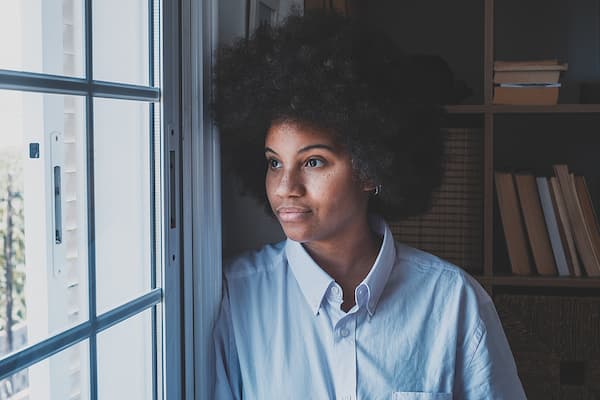 Young woman looking out window reflecting on emotions and mental health